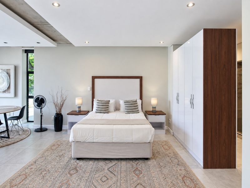 Modern bedroom featuring built-in cupboards, recessed downlighting, and a unique exposed concrete ceiling detail, creating a clean and contemporary living space.