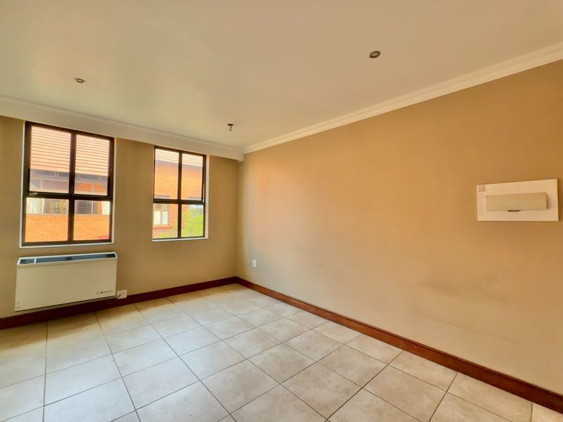 An empty bedroom featuring tiled flooring, recessed lighting, and a built-in air conditioning unit, offering a neutral canvas for personalization.