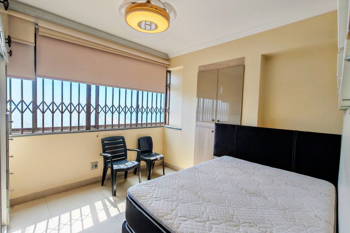 A bedroom featuring tiled flooring, a built-in wardrobe, and a window fitted with a security gate and roller blind.
