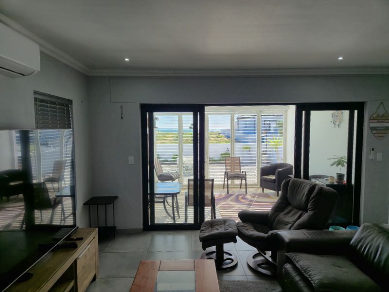 Spacious living room featuring large sliding glass doors that open onto a patio, providing natural light and views of the outdoor area.