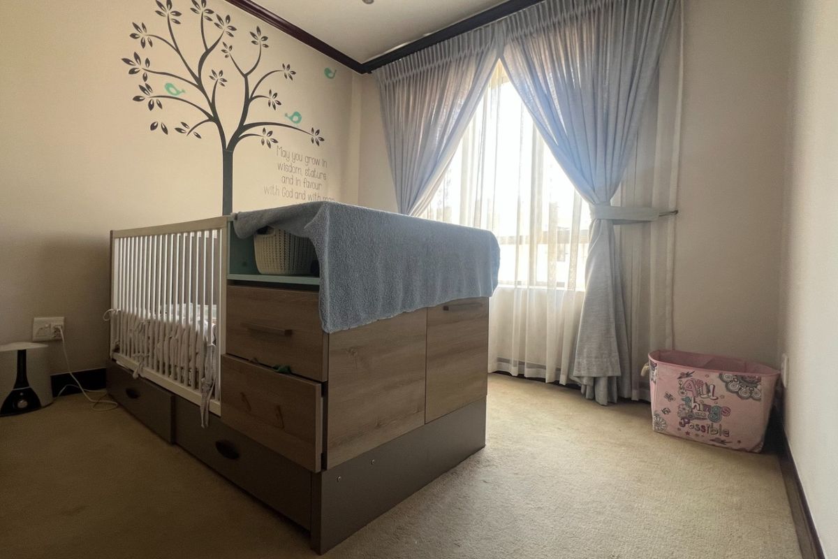 A bedroom featuring carpeted flooring, neutral wall finishes, and large windows with installed curtain tracks, providing natural light.