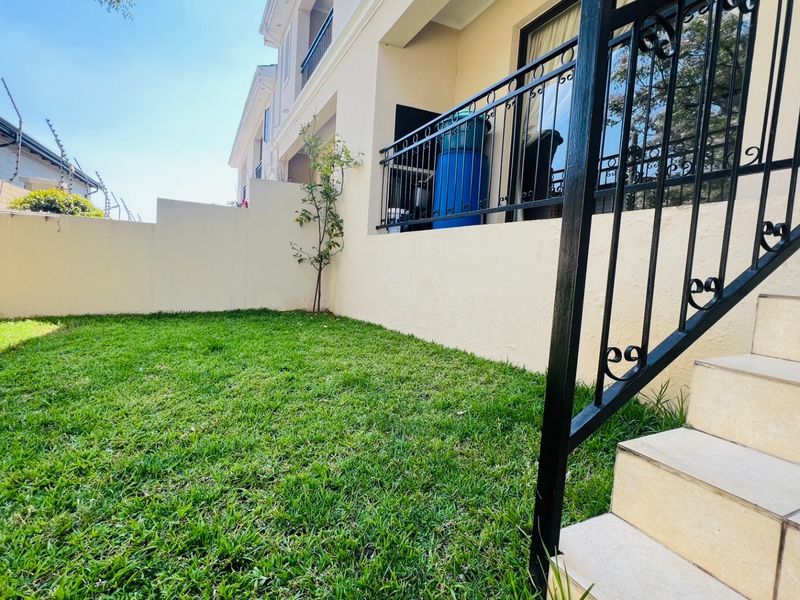 A private rear garden area featuring a manicured lawn, boundary walls with electric fencing, and a tiled staircase leading to the upper level.