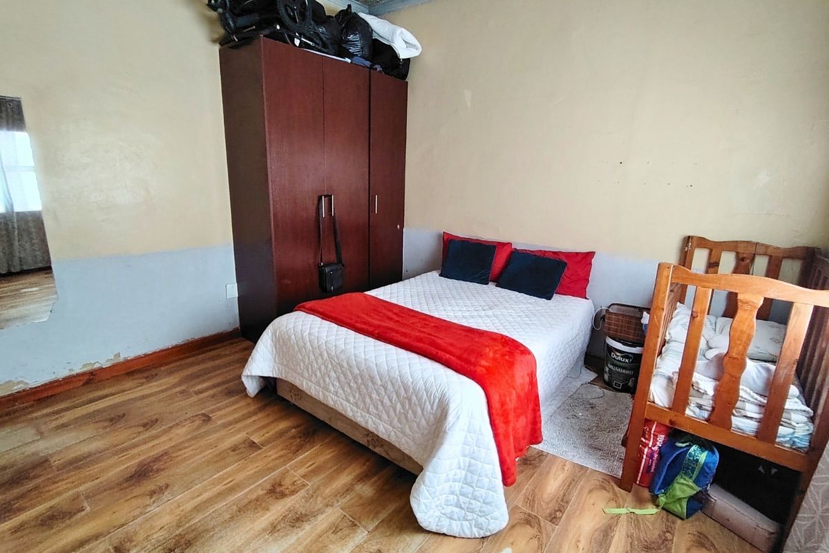 A bedroom featuring laminate flooring and two-tone wall finishes, requiring cosmetic updates to the wall surfaces.