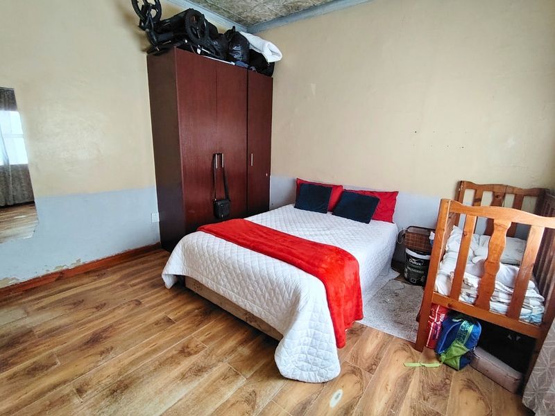A bedroom featuring laminate flooring and two-tone wall finishes, requiring cosmetic updates to the wall surfaces.