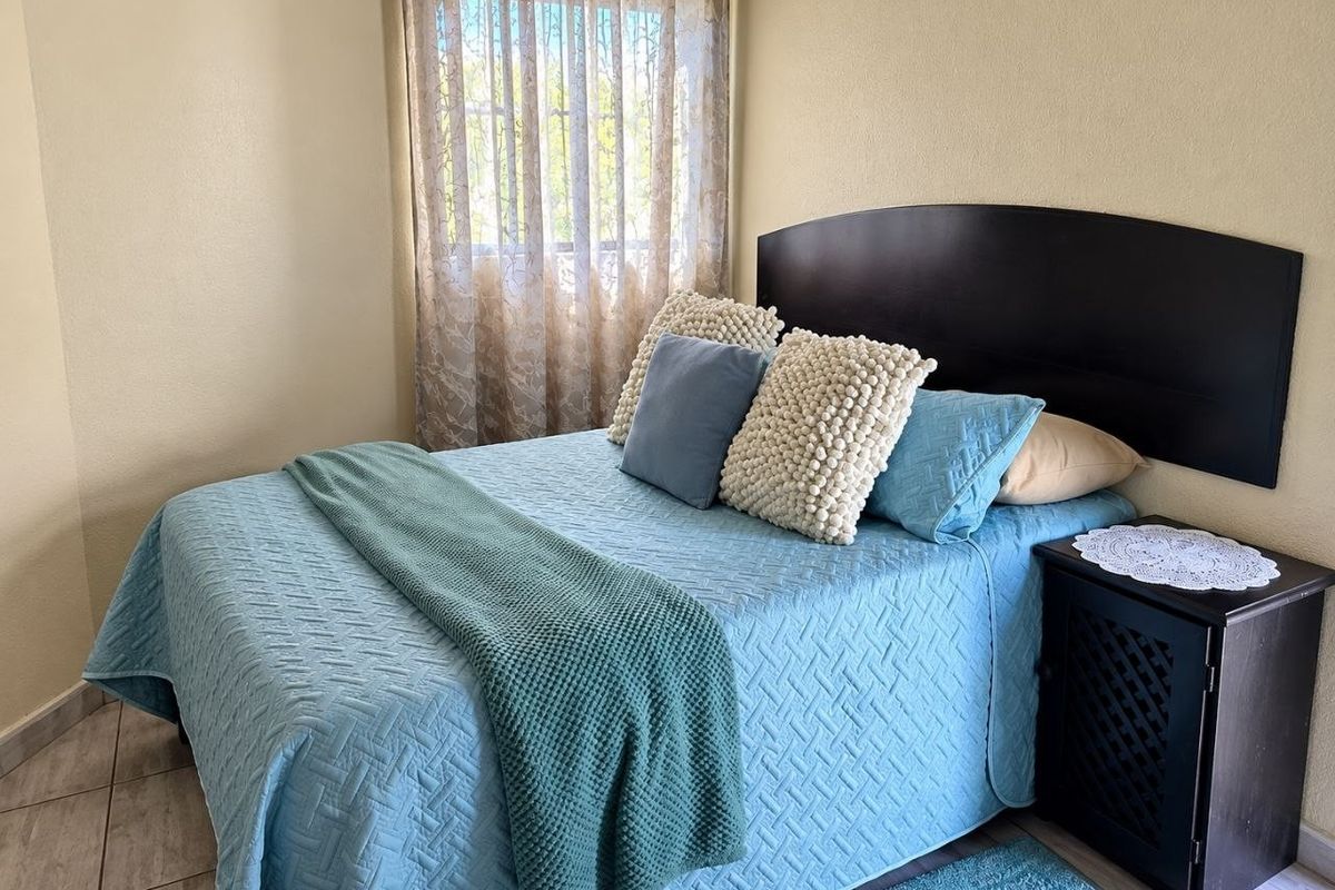 A cozy bedroom featuring tiled flooring and a window with natural light, providing a comfortable and functional living space.