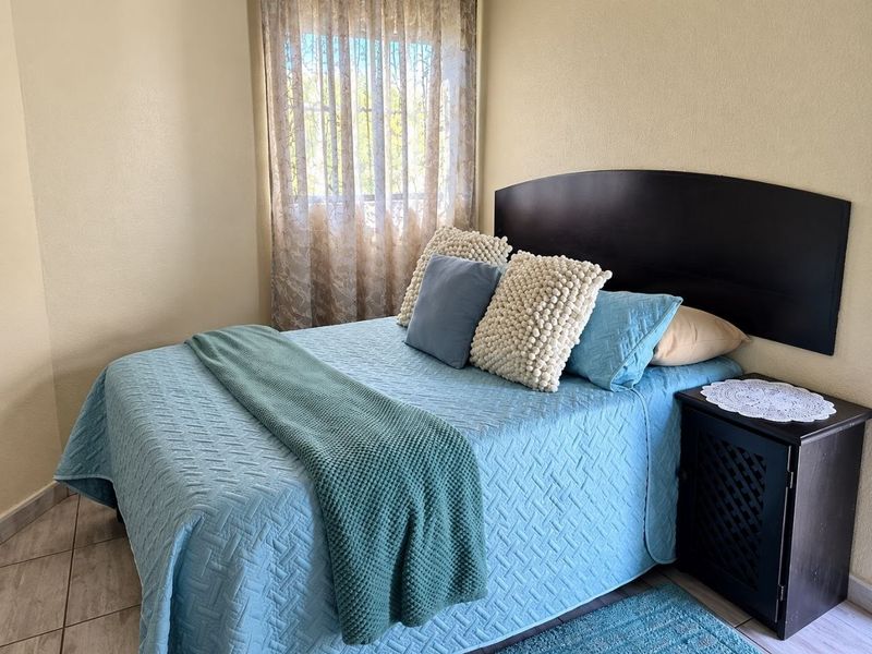 A cozy bedroom featuring tiled flooring and a window with natural light, providing a comfortable and functional living space.