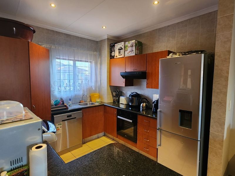 A functional kitchen featuring wood-finish cabinetry, granite countertops, a built-in oven, and a tiled backsplash, offering a practical layout for daily meal preparation.