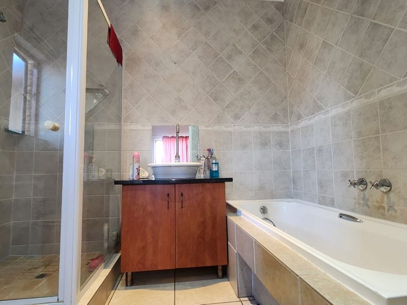 A functional bathroom featuring a shower enclosure, a built-in vanity with a vessel sink, and a bathtub with tiled surround.
