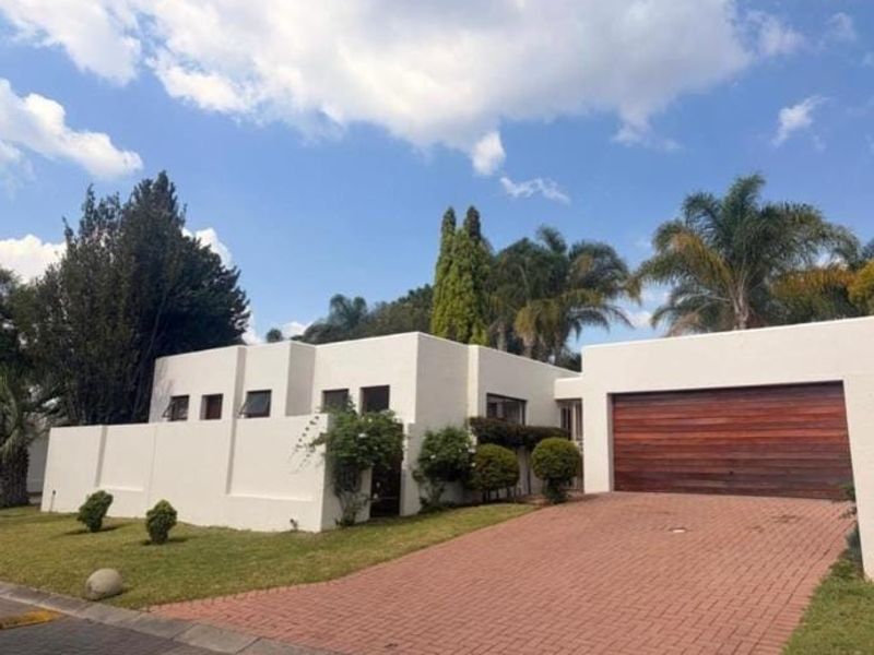 Front elevation of a modern house featuring a paved driveway, a prominent wooden garage door, and a clean white exterior finish.
