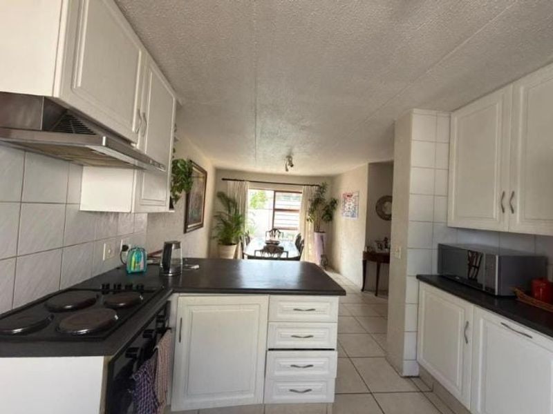 Open-plan kitchen and dining area featuring white cabinetry, dark countertops, and tiled flooring, creating a functional and connected living space.