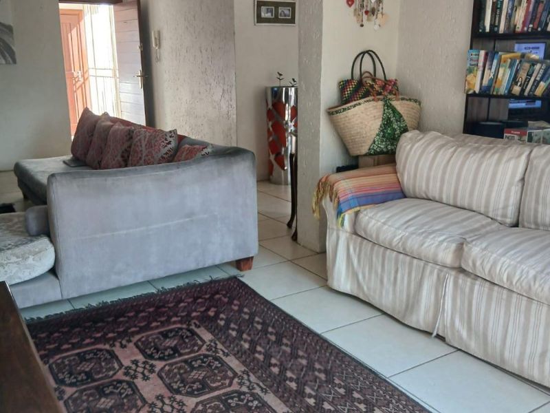 A living room area featuring tiled flooring and built-in shelving, showing signs of wear on the walls and ceiling.