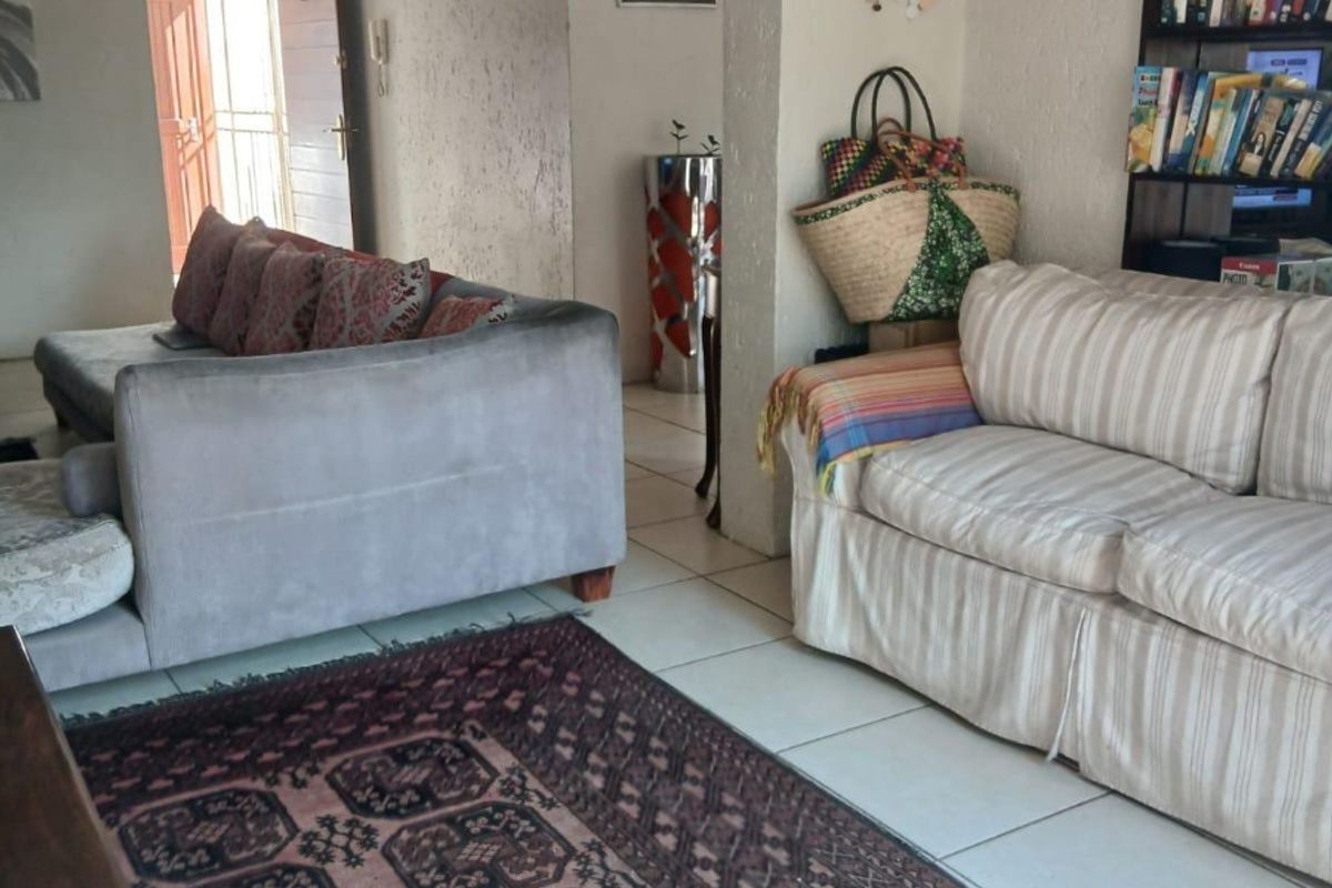 A living room area featuring tiled flooring and built-in shelving, showing signs of wear on the walls and ceiling.