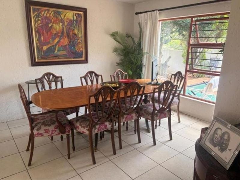 A dining room featuring tiled flooring and a large window with views of the outdoor pool area.