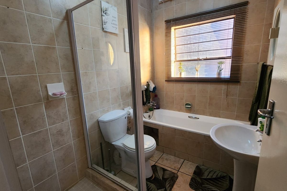 A functional bathroom featuring a shower enclosure, bathtub, pedestal basin, and tiled finishes throughout.