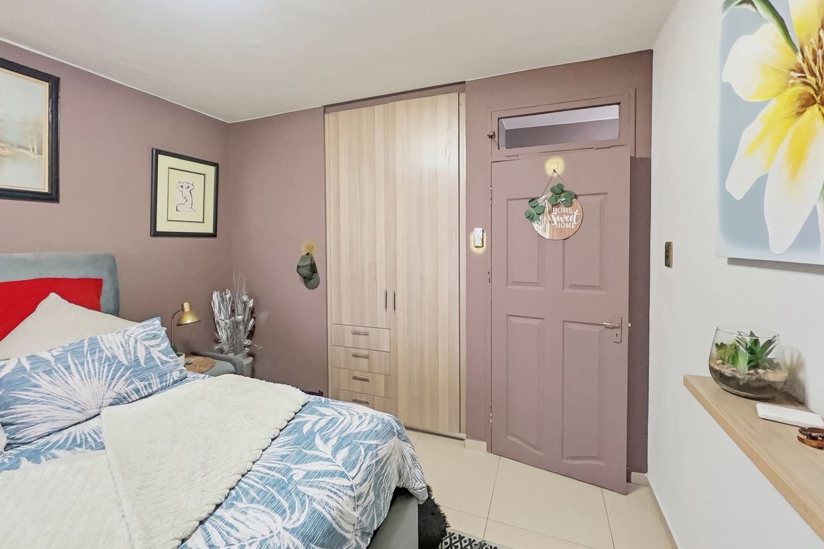 A well-maintained bedroom featuring a built-in wardrobe, tiled flooring, and a painted door with a transom window.
