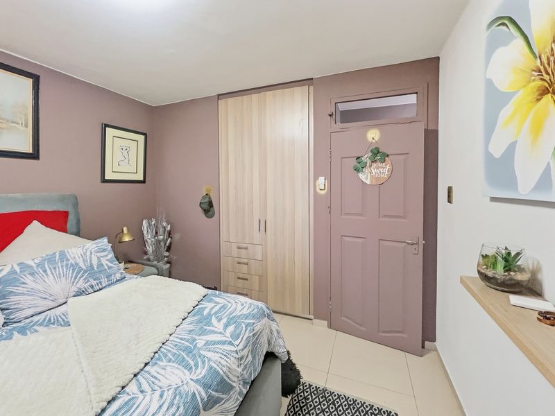 A well-maintained bedroom featuring a built-in wardrobe, tiled flooring, and a painted door with a transom window.