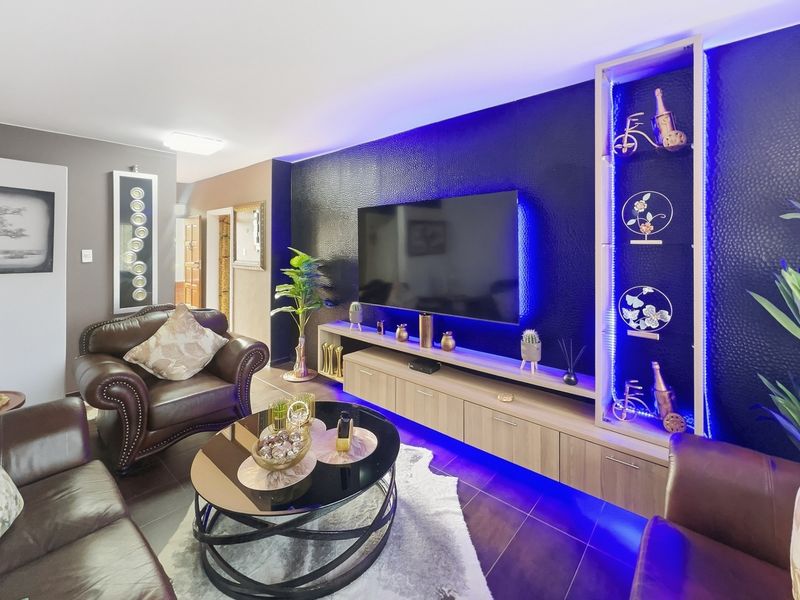 Modern living room featuring a custom built-in media unit with integrated LED accent lighting and dark textured feature wall.