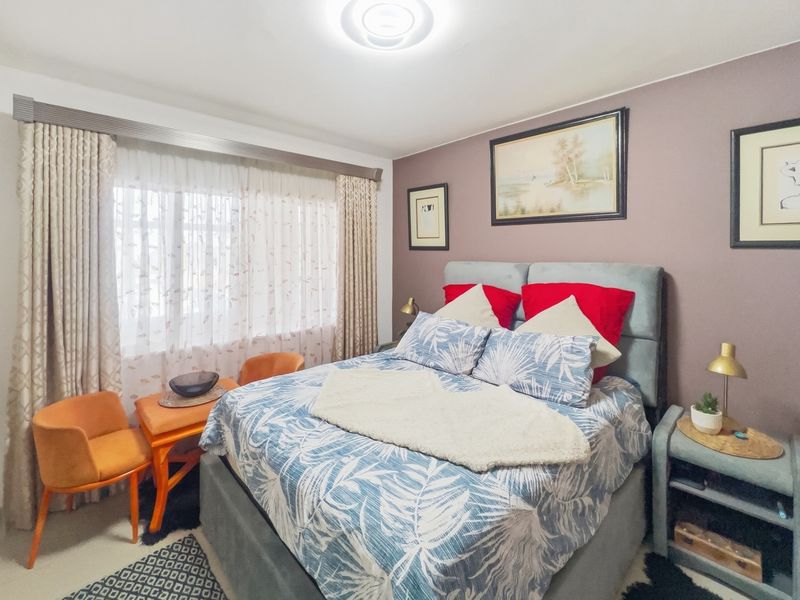A well-maintained bedroom featuring neutral wall tones, large window with curtain tracks, and a central ceiling light fixture.