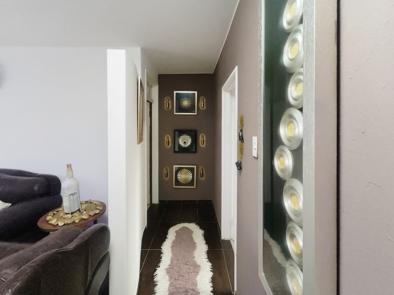 A well-maintained interior hallway featuring dark tiled flooring and a decorative recessed wall panel, providing access to adjacent rooms.