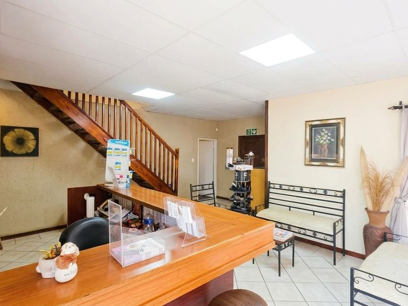 Office reception area featuring a wooden reception desk, tiled flooring, and a staircase leading to the upper level.