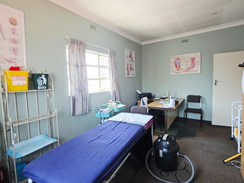 A functional office or consultation room featuring neutral wall paint, carpeted flooring, and standard window treatments, suitable for professional or medical use.