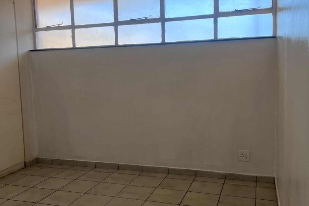 An empty bedroom featuring tiled flooring and high-level clerestory windows, providing a blank canvas for potential interior design and renovation.