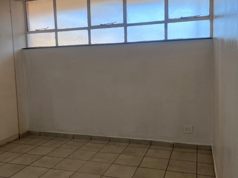 An empty bedroom featuring tiled flooring and high-level clerestory windows, providing a blank canvas for potential interior design and renovation.
