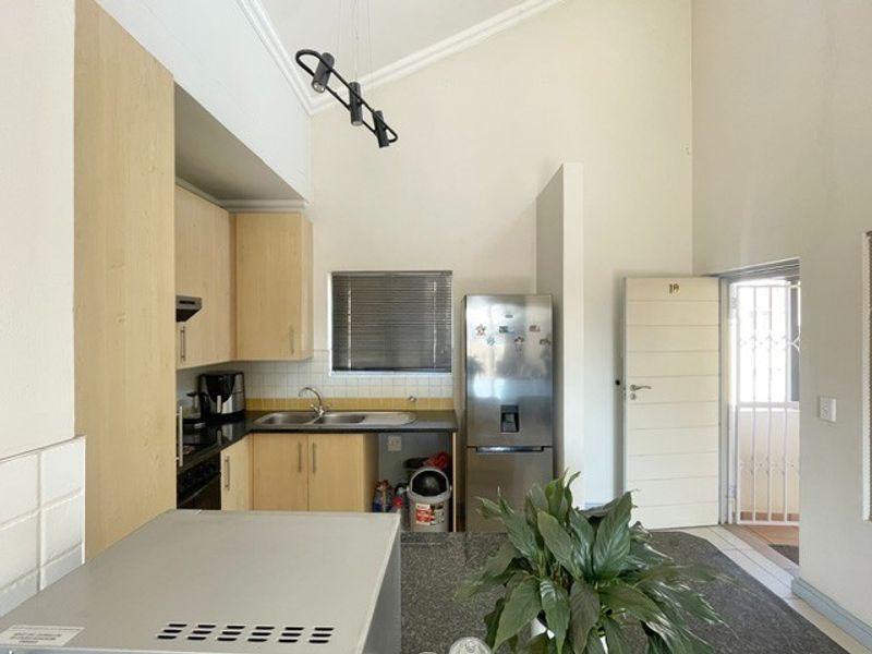 A functional kitchen featuring light wood-tone cabinetry, a tiled backsplash, and a vaulted ceiling, providing an open and airy feel to the apartment space.