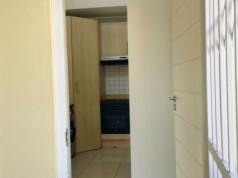A compact scullery or utility area featuring built-in cabinetry, a stove with an extractor fan, and tiled flooring.