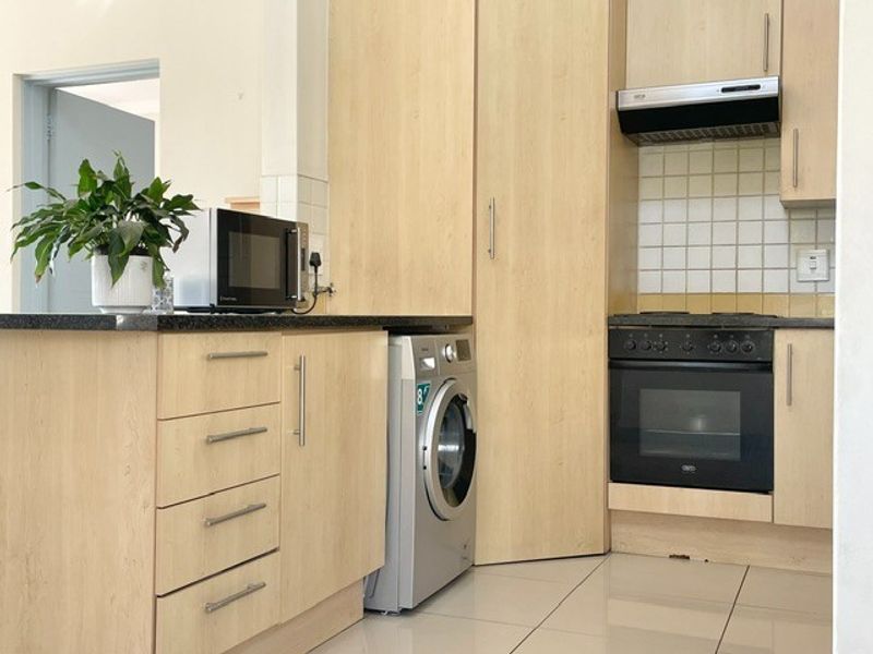 A functional kitchen featuring light wood cabinetry, granite countertops, a built-in oven with extractor fan, and tiled flooring.