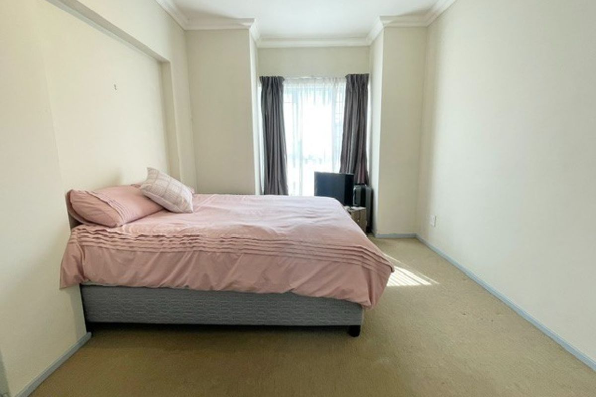 A simple bedroom featuring neutral walls, carpeted flooring, and cove molding, providing a blank canvas for potential interior updates.