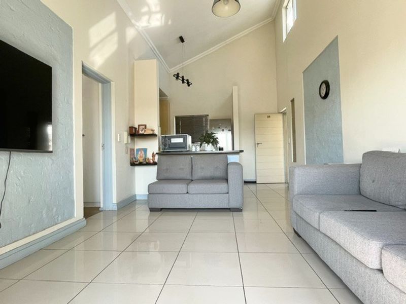 Open-plan living area featuring high vaulted ceilings, tiled flooring, and a functional kitchen counter layout, providing a bright and spacious living environment.