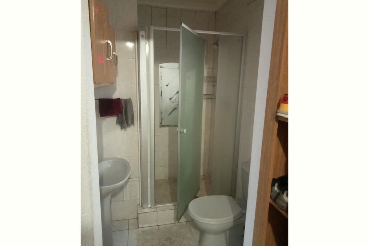 Compact bathroom featuring a pedestal sink, toilet, and a shower enclosure with tiled finishes throughout.
