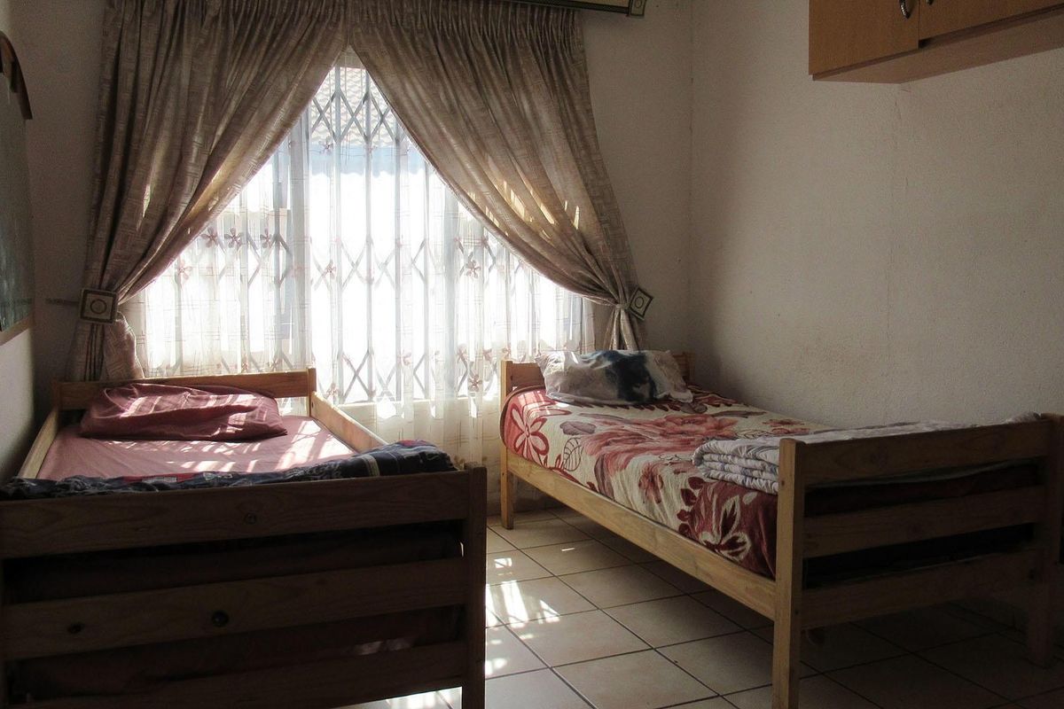 A bedroom featuring tiled flooring, a security gate on the window, and built-in storage, requiring cosmetic updates to improve its overall condition.