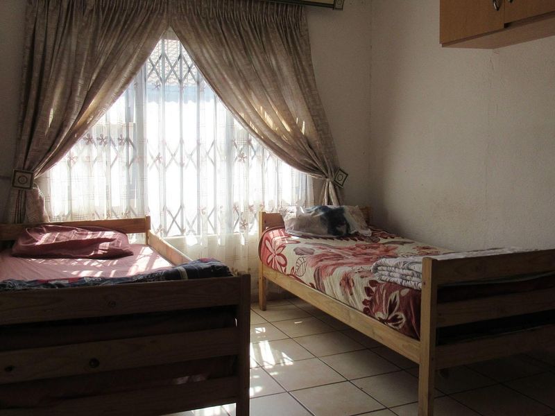 A bedroom featuring tiled flooring, a security gate on the window, and built-in storage, requiring cosmetic updates to improve its overall condition.