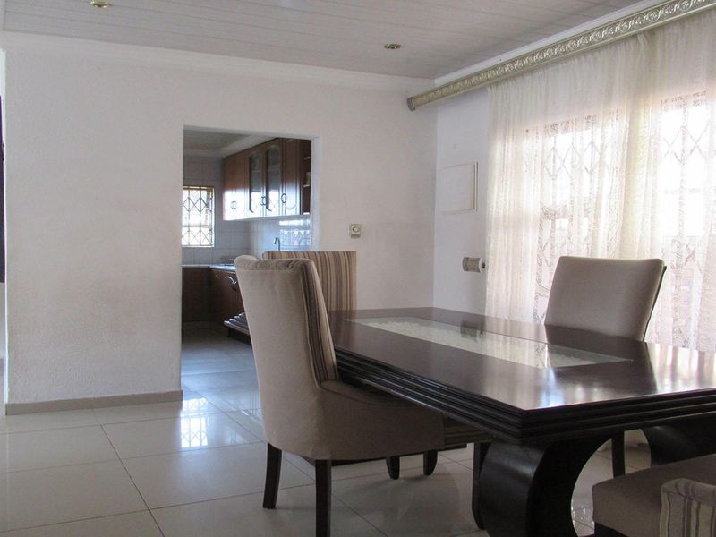 Open plan dining area featuring tiled flooring and coved ceilings, with a view through to the adjacent kitchen space.