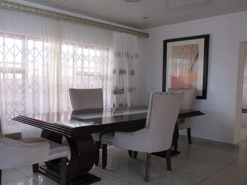A dining room featuring tiled flooring, a tongue and groove ceiling, and a large window fitted with a security gate.