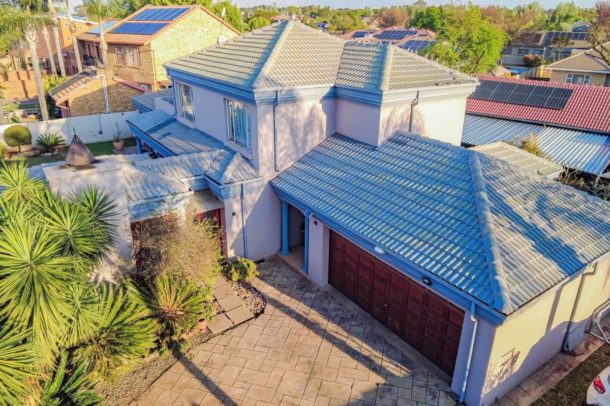 Aerial view of a two-story residential house featuring a tiled roof, paved driveway, and an integrated double garage.