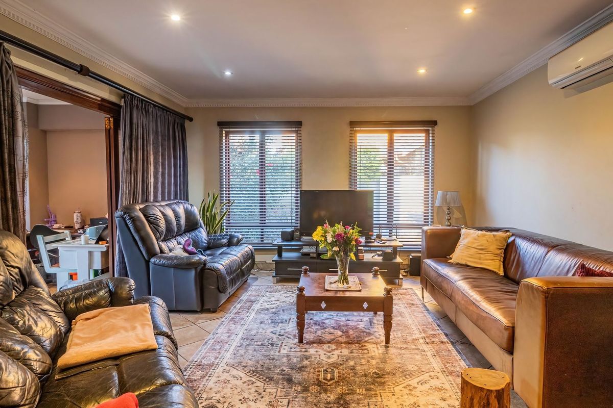 A comfortable living room featuring tiled flooring, recessed downlighting, crown molding, and a wall-mounted air conditioning unit.