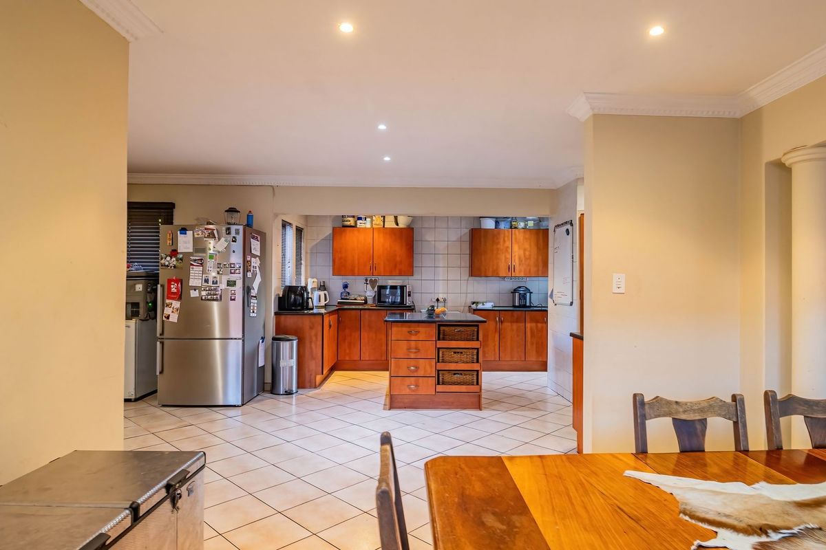 A functional kitchen featuring wooden cabinetry, a central island, tiled flooring, and recessed lighting, offering a practical layout for daily meal preparation.