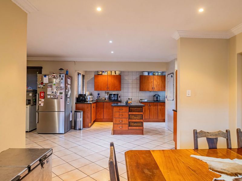 A functional kitchen featuring wooden cabinetry, a central island, tiled flooring, and recessed lighting, offering a practical layout for daily meal preparation.
