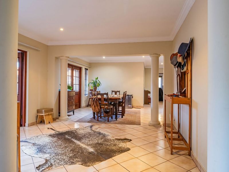 Spacious open-plan living and dining area featuring tiled flooring, decorative columns, and crown molding, creating a bright and inviting atmosphere.
