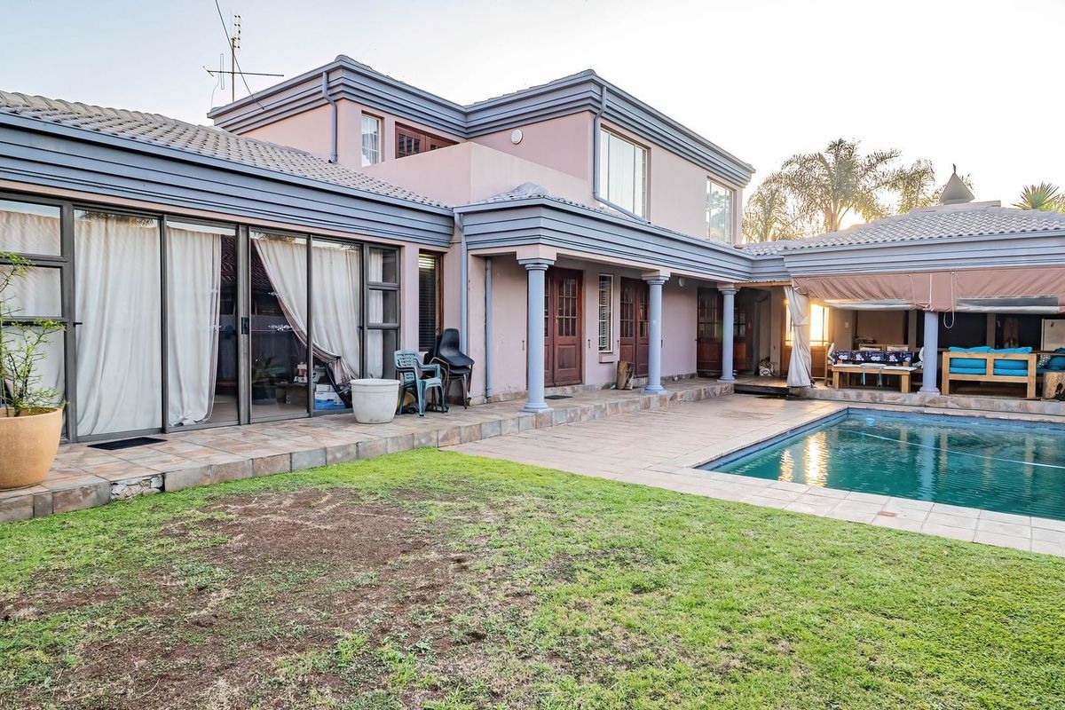 Rear view of the house featuring a swimming pool, covered patio area, and established garden with sliding door access to the main living spaces.