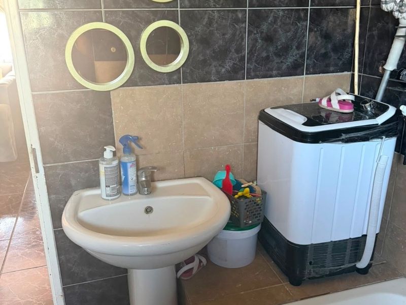 A functional laundry area featuring a pedestal basin and tiled wall finishes, providing a practical utility space within the home.