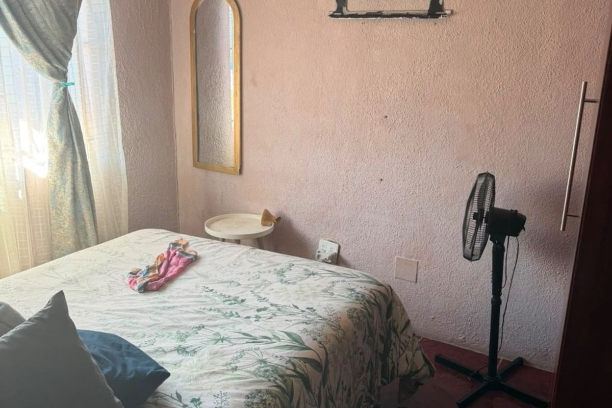 A bedroom featuring tiled flooring and built-in wardrobe storage, currently requiring cosmetic updates to the wall finishes.