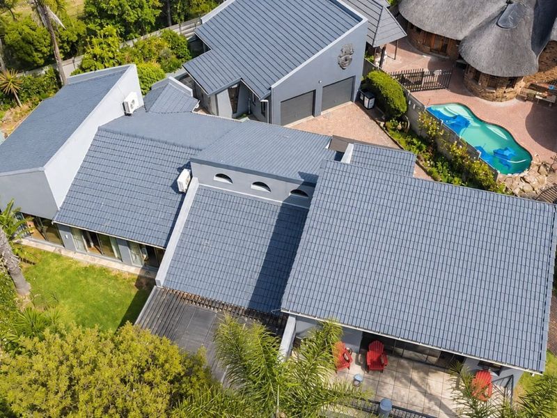 Aerial view of a residential property featuring a large tiled roof, swimming pool, double garage, and paved outdoor entertainment areas.