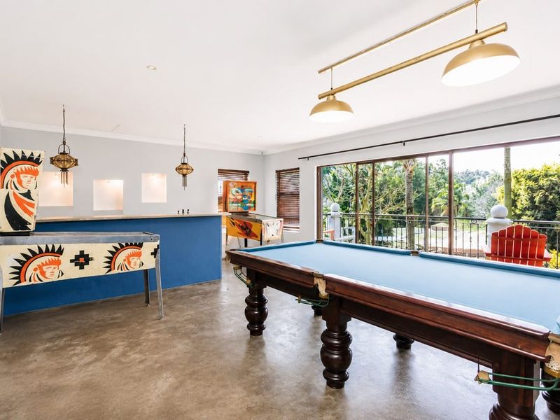 Spacious entertainment room featuring a built-in bar, polished concrete floors, and large sliding doors opening to a balcony with scenic views.