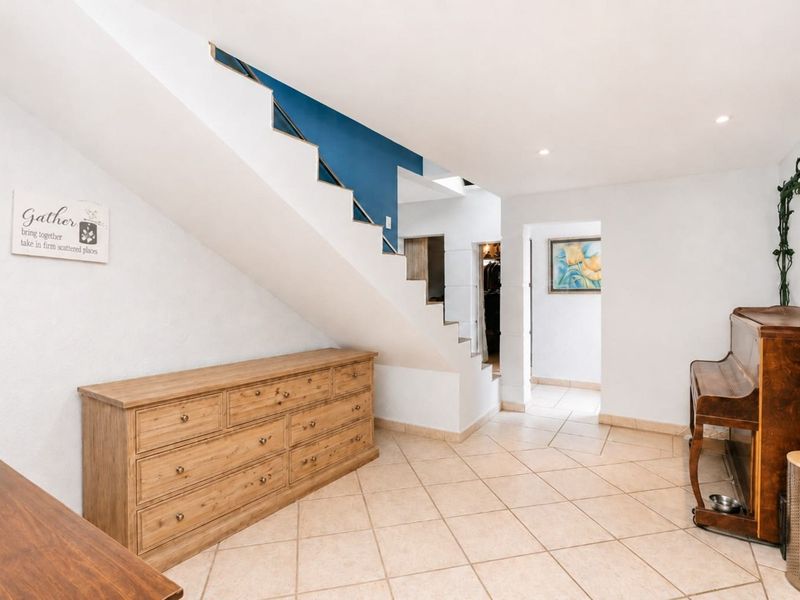 A spacious hallway featuring tiled flooring and an open staircase with a blue accent wall, providing access to adjacent living areas.