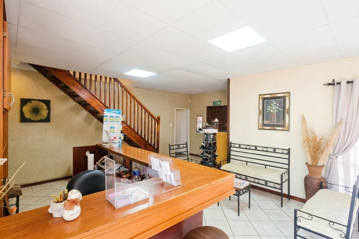 An entry area featuring a wooden staircase, reception counter, tiled flooring, and a drop ceiling with recessed lighting.