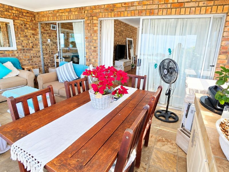 A covered patio area featuring exposed brick walls, tiled flooring, and large sliding glass doors providing access to the interior living space.